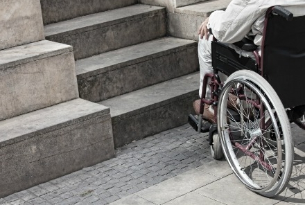 Disabile su sedia a rotelle di fronte a rampa di scale